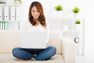 smiling Young woman sitting on the sofa with laptop