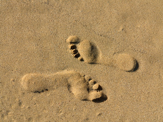 Gegenläufige Fußspuren im Sand