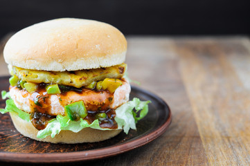 Homemade fish burger with salmon, avocado and pineapple.Close up