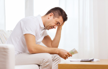 Obraz premium man with money and calculator at home