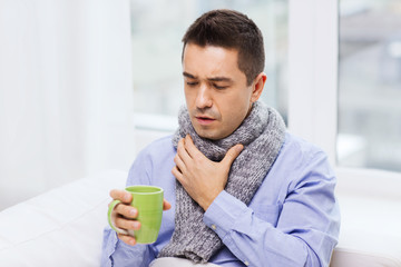 ill man with flu drinking tea and coughing at home - obrazy, fototapety, plakaty