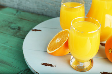 Glass of orange juice with slices on color wooden background
