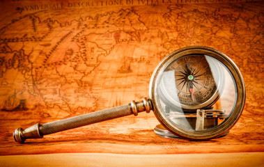 Vintage magnifying glass lies on an ancient world map