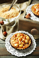 Mini cakes with nuts on napkin on wooden background