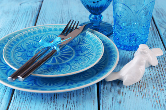 Empty colorful plate, glasses and silverware set on wooden