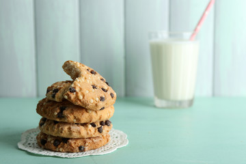 Tasty cookies and glass of milk on color wooden background