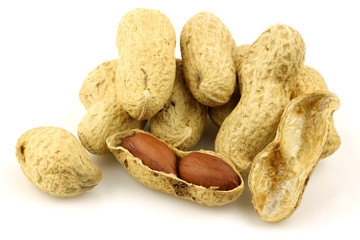 roasted peanuts and a peeled one on a white background