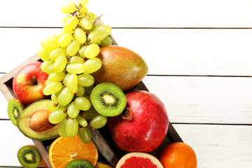 Assortment of fruits in box on wooden table