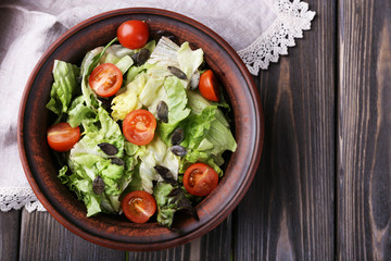Salad with arugula and cherry tomatoes on wooden table