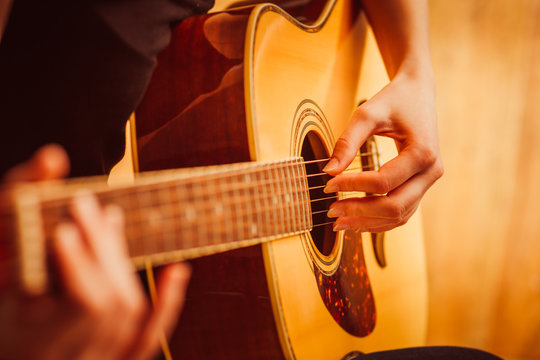 woman's hands playing acoustic guitar, close up