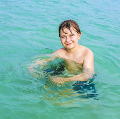 young   boy with brown hair enjoys swimming