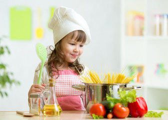 Cook kid makes healthy vegetables meal in the kitchen