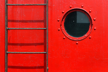 porthole and ladder on a  red ship