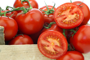 tomatoes on the vine in a wooden crate on a white background