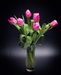 Bouquet of tulips in glass vase on black background