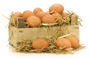  fresh brown eggs and some straw in a wooden crate