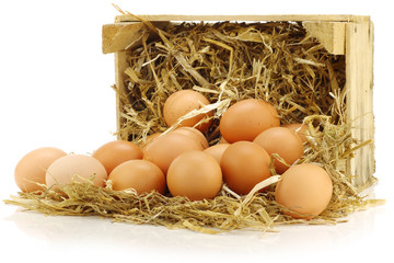 bunch of fresh brown eggs and some straw in a wooden crate