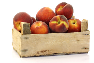 peaches in a wooden crate on a white background