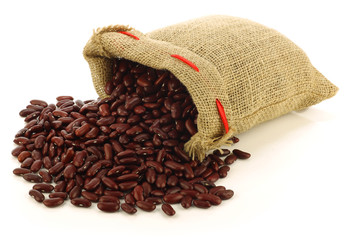 red kidney beans in a burlap bag on a white background