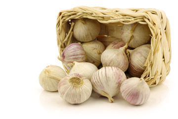 Fototapeta premium fresh garlic bulbs in a woven basket on a white background