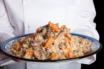 Turkish dish with pilaf in the hands of the cook