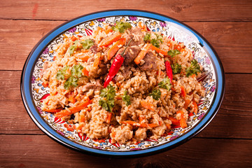 Delicious pilaf on a turkish plate on old wooden table. Rustic s