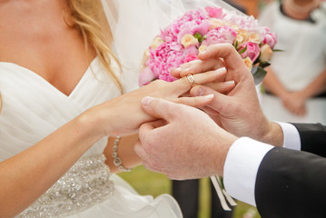 groom putting ring on bride's finger