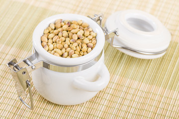 Coriander - Dried coriander seeds in a white jar.
