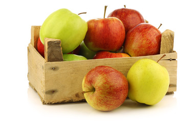 assorted fresh apples in a wooden crate on a white background