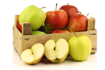 assorted fresh apples in a wooden crate on a white background