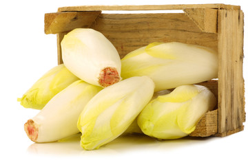 fresh chicory in a wooden crate on a white background
