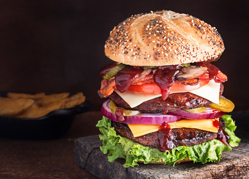 Double decker cheeseburger with many ingredients on seeded bun