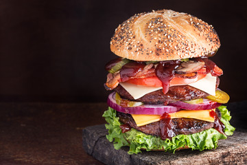Double decker cheeseburger with many ingredients on seeded bun - obrazy, fototapety, plakaty