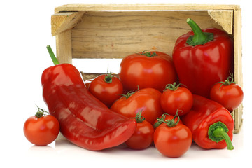 red sweet peppers and tomatoes in a wooden crate