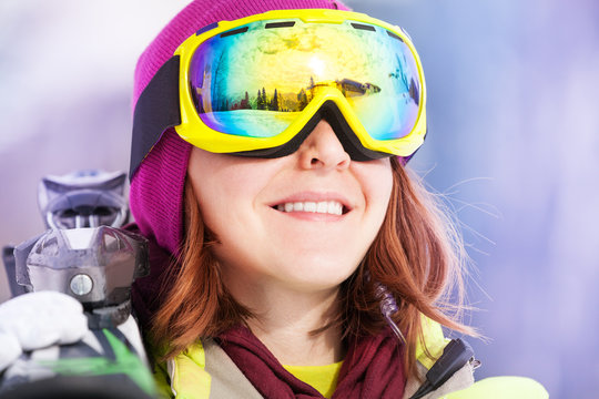 Portrait of young woman in mask holding ski