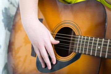 Teenage Boy plays an acoustic guitar