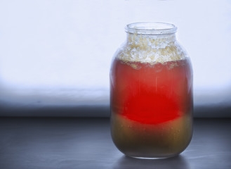 Big jar of half crystallized honey on a windowsill