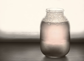 Big jar of half crystallized honey on a windowsill