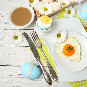 Easter table setting with flowers and eggs on old wooden table