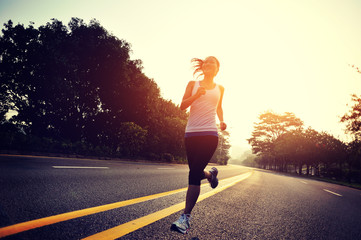 young woman runner running at sunrise road  