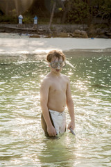 young boy wearing a diving mask is walking at the beautiful beac