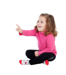 Cute little girl sitting on the floor pointing something with th