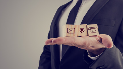 Businessman holding three wooden cubes with contact symbols
