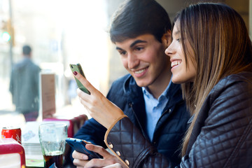 Young couple using mobile phone in cafe.