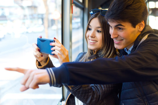 Young couple taking selfies with smartphone at bus.