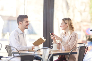 Two young business people sitting in a cafe