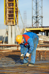 Builder making reinforcement for concrete