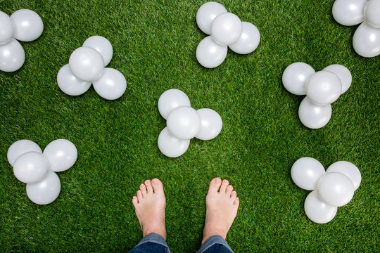 Mens feet standing on grass with white baloons