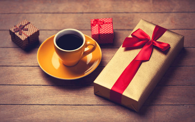 Cup of coffee and gift boxes on a wooden table.