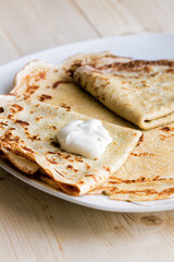 plate of pancakes and sour cream on a wooden table